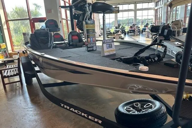 Slide: The Image of 2025 Tracker Savage 215 boat displayed indoors on a trailer, showcasing sleek design and seating. - 2