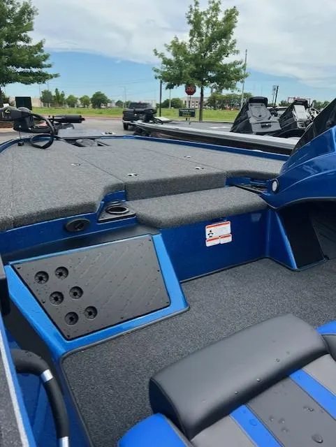 Slide: The Image of 2025 Nitro Z19 boat interior with blue accents and seating, parked outdoors. - 7