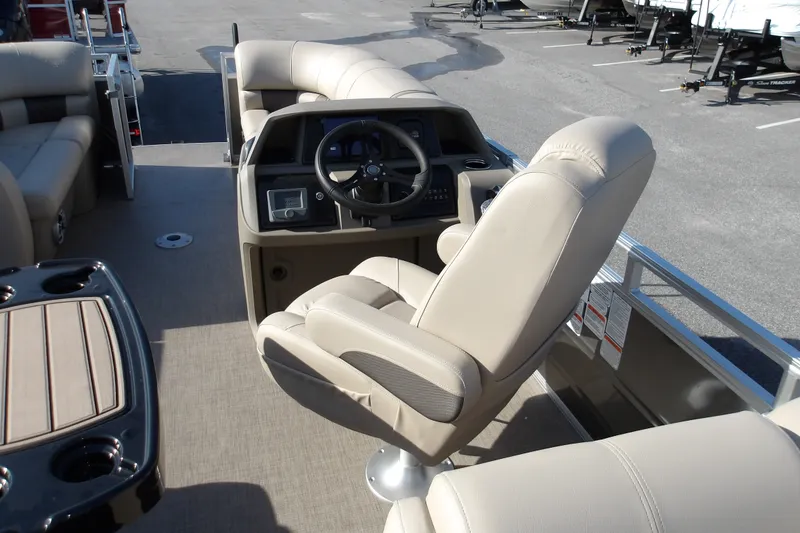 Slide: The Image of 2025 Sun Tracker Party Barge 22 RF DLX interior with beige seating and steering console. - 22
