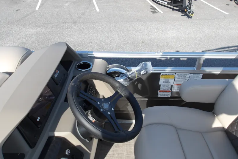 Slide: The Image of 2025 Sun Tracker Party Barge 22 RF DLX steering console with beige seating and controls. - 19
