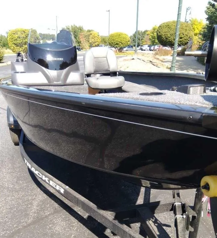 Slide: The Image of 2025 Tracker Super Guide V-16 SC boat on trailer, sleek black design, outdoor setting. - 2