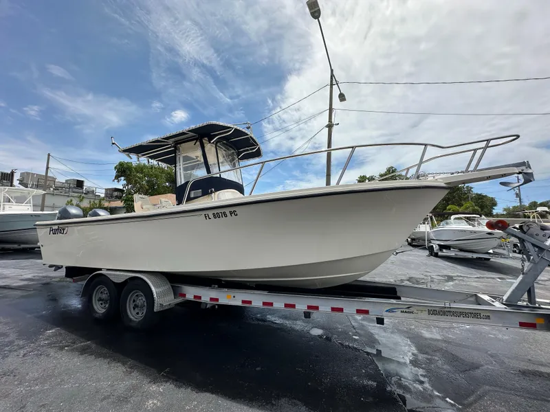 Slide: The Image of 2011 Parker 25 boat on trailer, parked outdoors under a cloudy sky. - 10