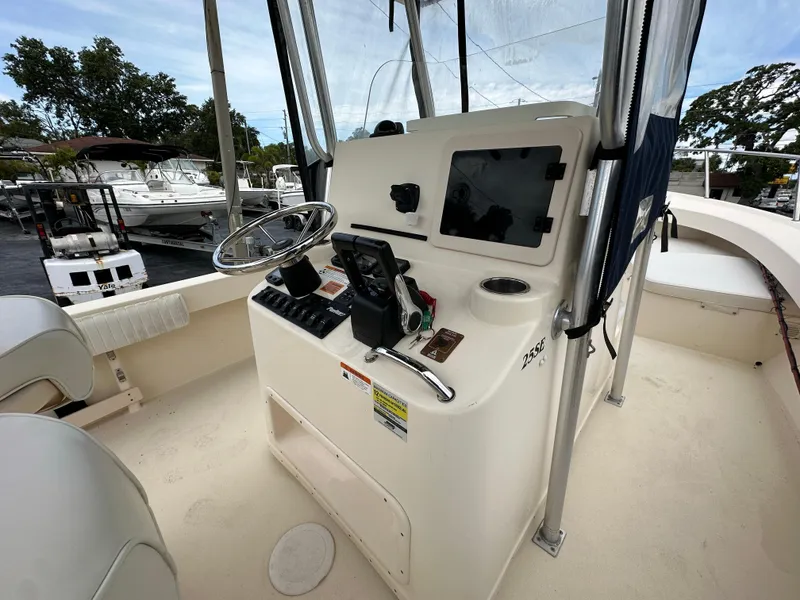 Slide: The Image of 2011 Parker 25 boat helm with steering wheel, controls, and navigation equipment at marina. - 11