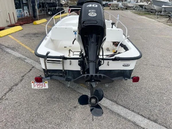 Slide: The Image of 2005 Boston Whaler 130 Sport boat, rear view with outboard motor, parked on pavement. - 5