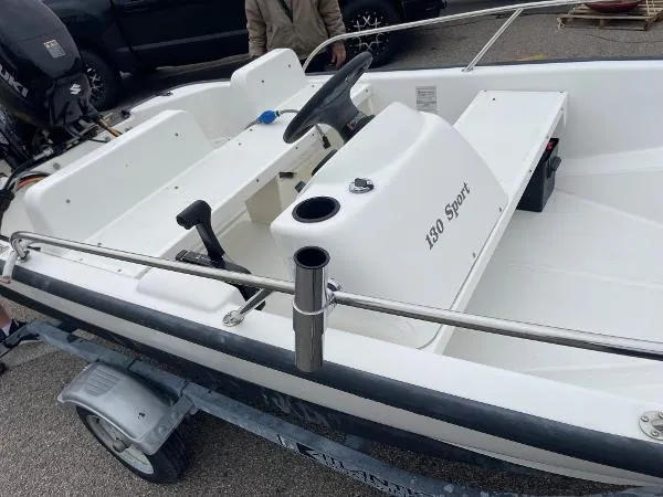 Slide: The Image of 2005 Boston Whaler 130 Sport boat interior, featuring steering console and seating on a trailer. - 9