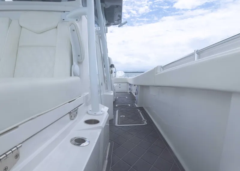 Slide: The Image of 2023 Invincible 33 Catamaran deck view with sleek white seating and ocean backdrop. - 22