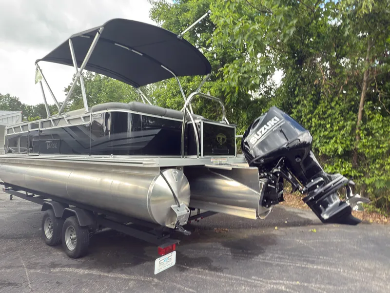 Slide: The Image of 2024 Tahoe Pontoon Sport Cruise with Suzuki outboard motor on trailer, parked outdoors. - 13