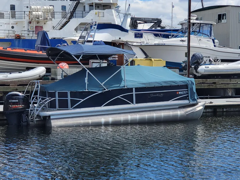 Slide: The Image of 2017 Godfrey Sweetwater 215c pontoon boat docked with cover, surrounded by other boats. - 19