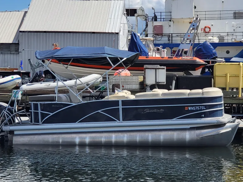 Slide: The Image of 2017 Godfrey Sweetwater 215c pontoon boat docked at a marina with a blue canopy. - 2