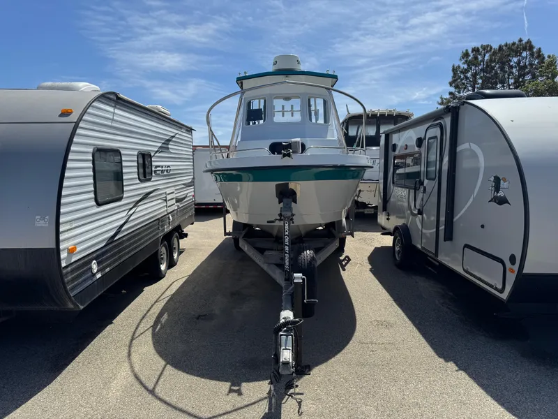Slide: The Image of 2001 Davis 22 Cortez boat on trailer between two RVs under a clear sky. - 16