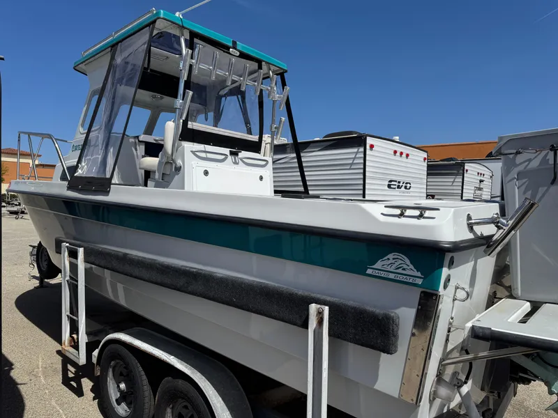 Slide: The Image of 2001 Davis 22 Cortez boat on trailer, featuring a cabin and teal accents. - 2