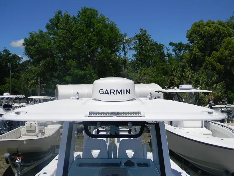 Slide: The Image of 2025 Sportsman Open 302 Center Console boat with Garmin radar, surrounded by trees and other boats. - 13