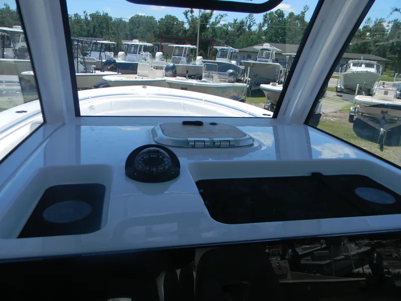 Slide: The Image of 2025 Sportsman Open 302 Center Console boat dashboard with compass and storage compartments. - 20