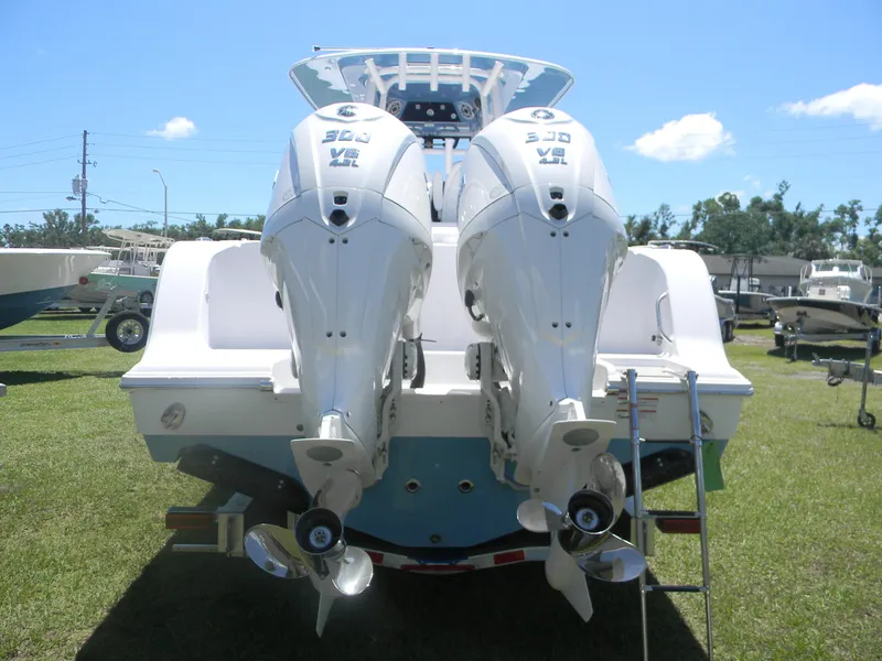 Slide: The Image of 2025 Sportsman Open 302 Center Console with twin outboard engines, rear view on grass. - 5