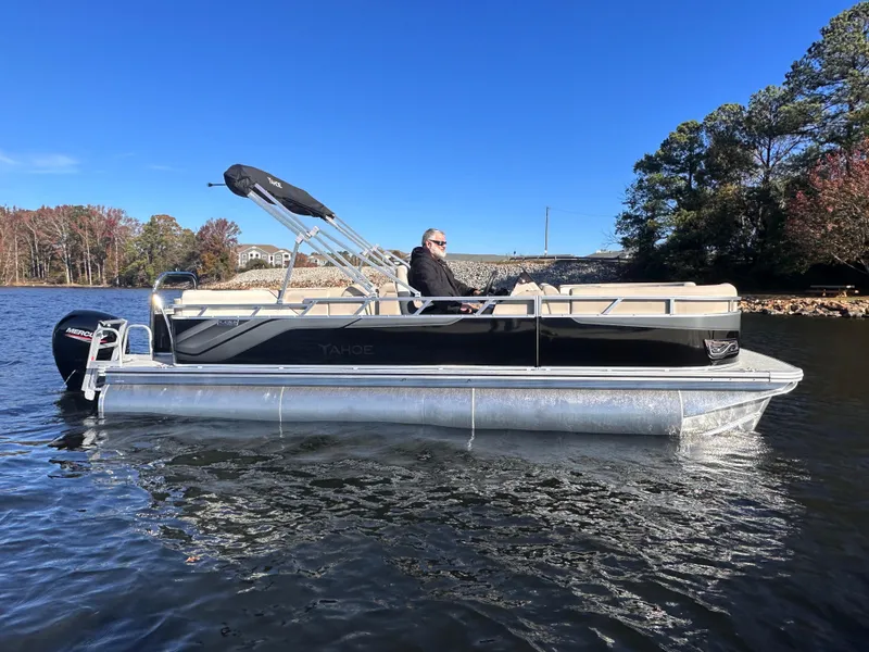 Slide: The Image of 2025 Tahoe Pontoon Sport 85 Quad Lounger on a serene lake with clear blue sky. - 1