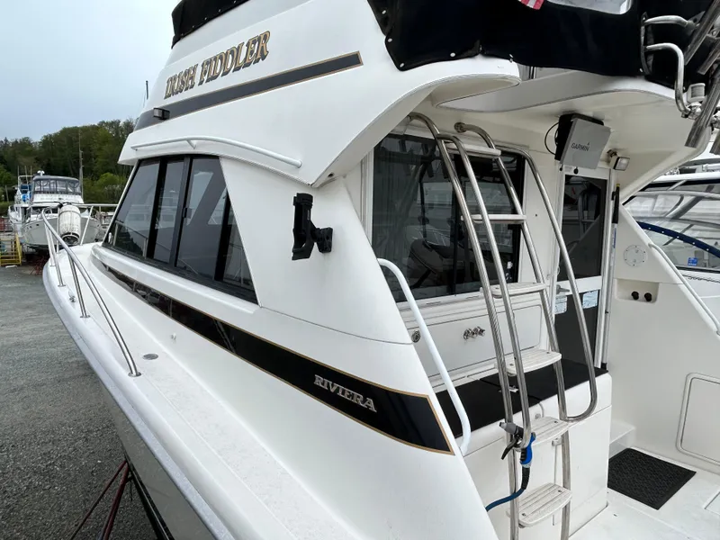 Slide: The Image of Riviera 34 Convertible yacht, 2000 model, docked with visible ladder and sleek design. - 12