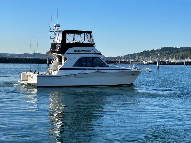 Slide: The Image of Riviera 34 Convertible boat from 2000 on calm water, with marina in background. - 2