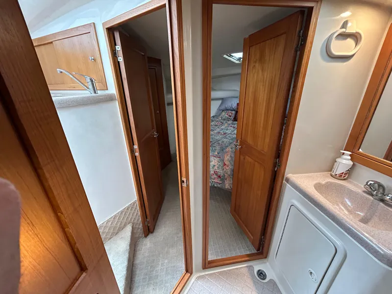 Slide: The Image of Interior of 2000 Riviera 34 Convertible yacht, featuring bathroom and bedroom with wooden doors. - 24