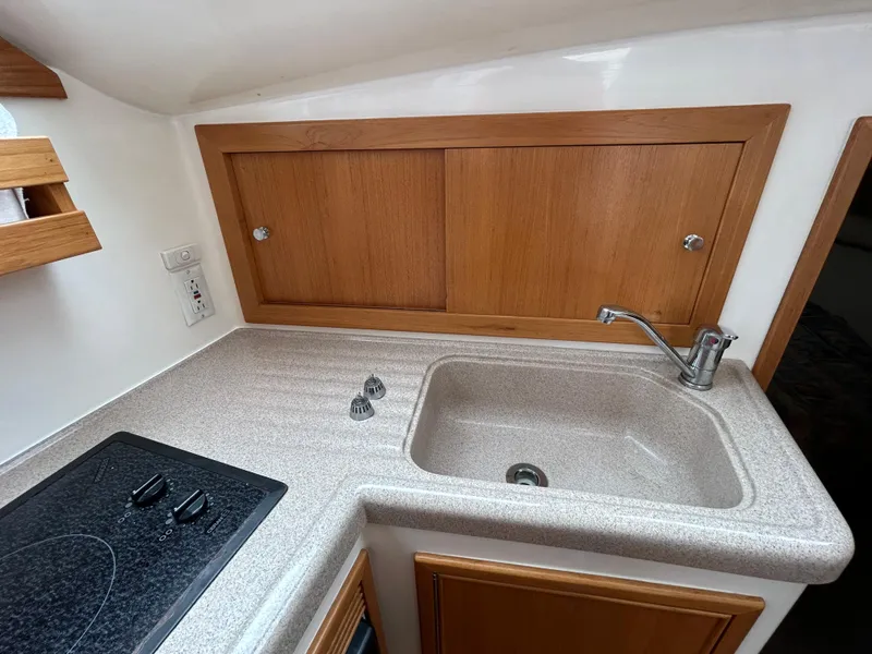 Slide: The Image of Compact kitchen area in a 2000 Riviera 34 Convertible boat with sink and stove. - 28