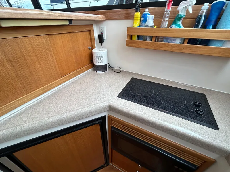 Slide: The Image of Compact kitchen area in a 2000 Riviera 34 Convertible boat with electric stove and wooden cabinetry. - 29