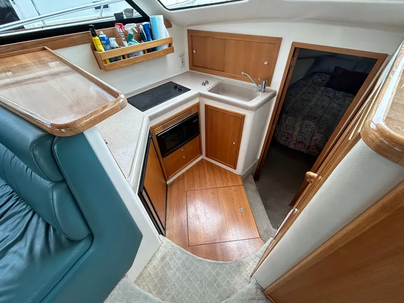 Slide: The Image of Compact kitchen area in a 2000 Riviera 34 Convertible boat with wood cabinetry and modern amenities. - 32