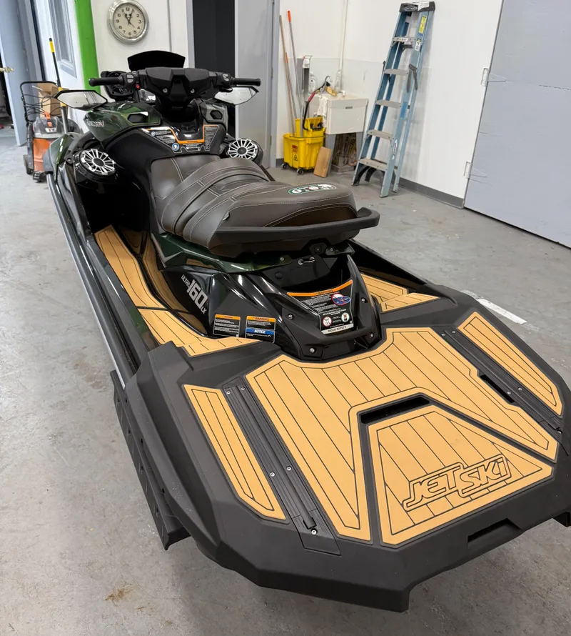 Slide: The Image of 2025 Kawasaki ULTRA 160 LX jet ski in a garage, featuring sleek design and wood-style deck. - 5