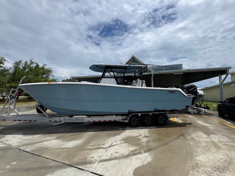 Slide: The Image of 2022 Invincible 33 Catamaran on trailer, parked outdoors under cloudy sky. - 1