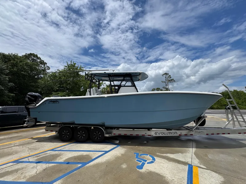 Slide: The Image of 2022 Invincible 33 Catamaran on trailer, parked outdoors under cloudy sky. - 11