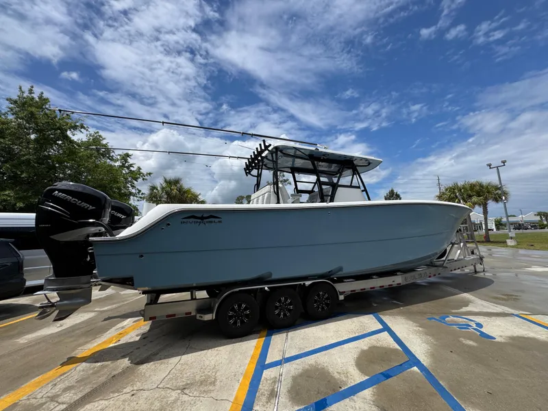 Slide: The Image of 2022 Invincible 33 Catamaran on trailer under blue sky, parked in lot. - 12