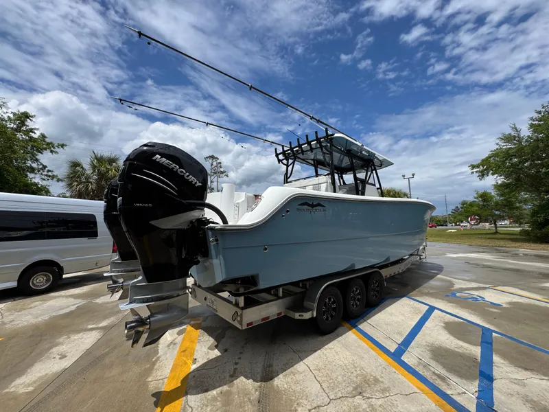Slide: The Image of 2022 Invincible 33 Catamaran on trailer, parked outdoors under a partly cloudy sky. - 13