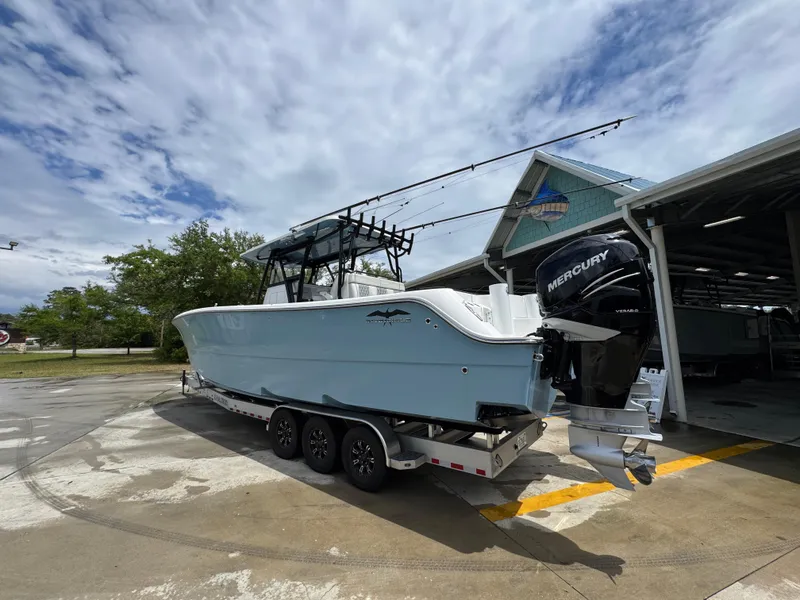 Slide: The Image of 2022 Invincible 33 Catamaran on trailer, parked outdoors near a boat garage. - 18