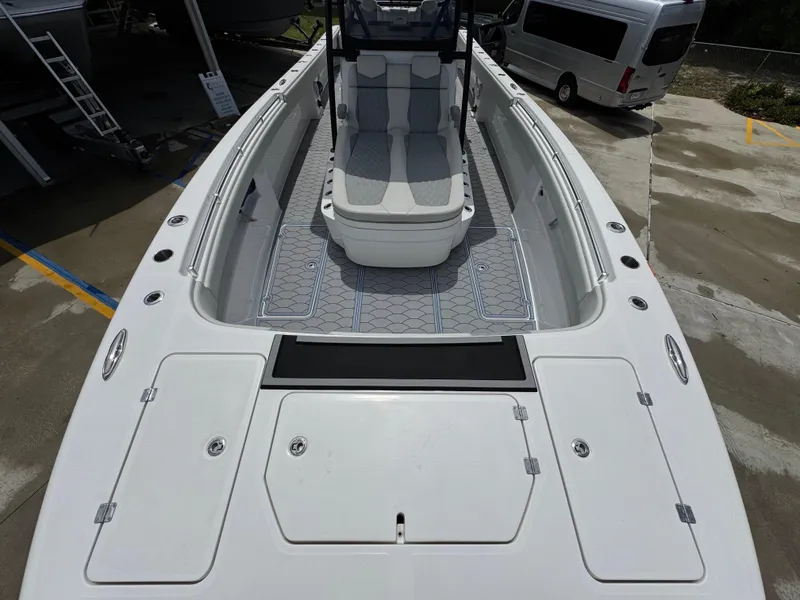 Slide: The Image of 2022 Invincible 33 Catamaran boat with spacious deck and seating, docked near a van. - 19