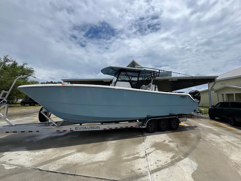 Slide: The Image of 2022 Invincible 33 Catamaran on trailer, parked outdoors under cloudy sky. - 2