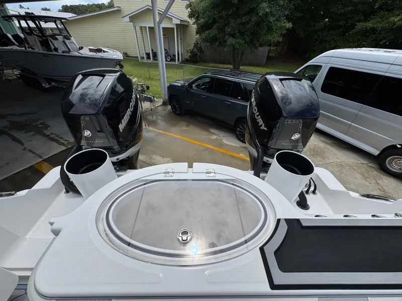 Slide: The Image of 2022 Invincible 33 Catamaran with dual outboard engines, parked near vehicles. - 40