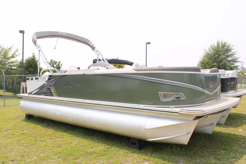 The Image of 2021 Tahoe LTZ Cruise pontoon boat on grass, featuring sleek design and canopy. - 1