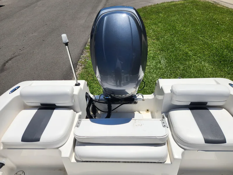 Slide: The Image of 2014 Tidewater 196 DC boat with outboard motor and cushioned seating, parked on grass. - 10