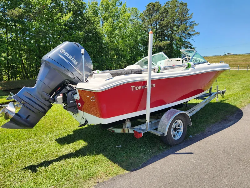 Slide: The Image of Red 2014 Tidewater 196 DC boat on trailer with Yamaha outboard motor, parked on grass. - 2