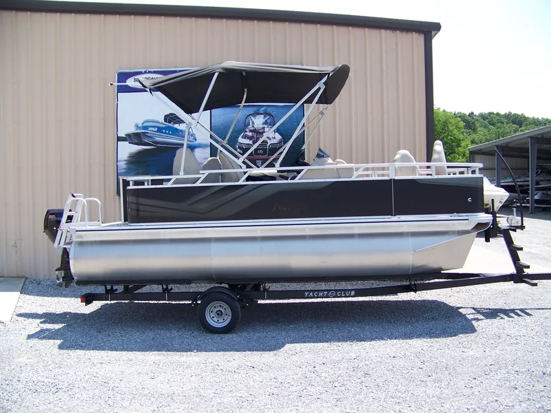 The Image of 2025 Avalon VTX Quad Fish pontoon boat on trailer, parked outside a building. - 1
