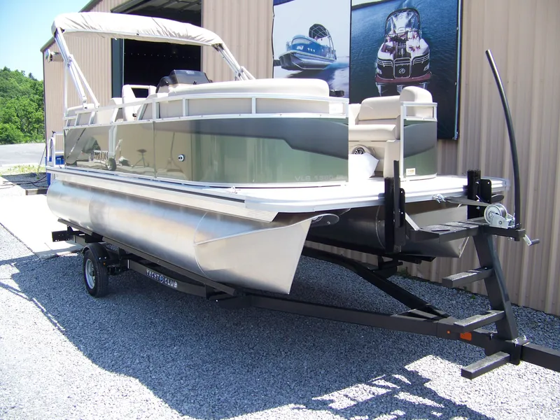 Slide: The Image of 2025 Avalon VLS Quad Lounge pontoon boat on trailer, parked outside a building. - 3