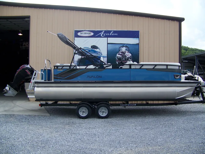 The Image of 2025 Avalon VENTURE 85 CRUISE pontoon boat on trailer outside a warehouse. - 1