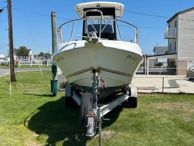 Slide: The Image of 2003 Aquasport 250 Osprey boat on trailer, parked on grass near residential area. - 2