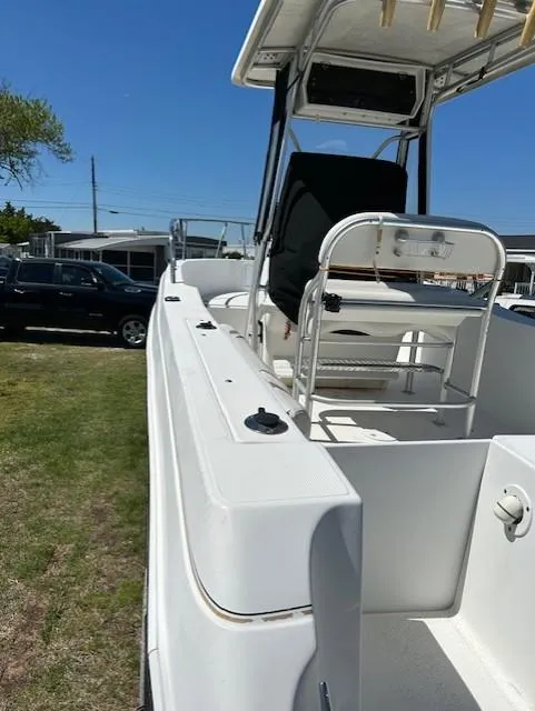 Slide: The Image of 2003 Aquasport 250 Osprey boat with seating, parked on grass under clear blue sky. - 6