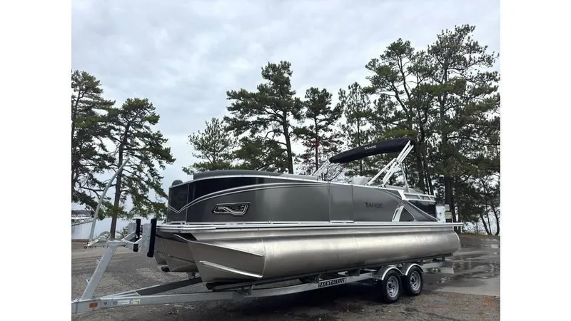 Slide: The Image of 2025 Tahoe Pontoon LTZ Quad Lounger on trailer, parked outdoors near trees. - 1