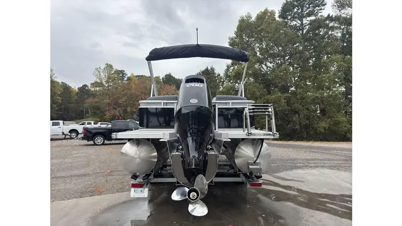 Slide: The Image of 2025 Tahoe Pontoon LTZ Quad Lounger with outboard motor, parked outdoors. - 3