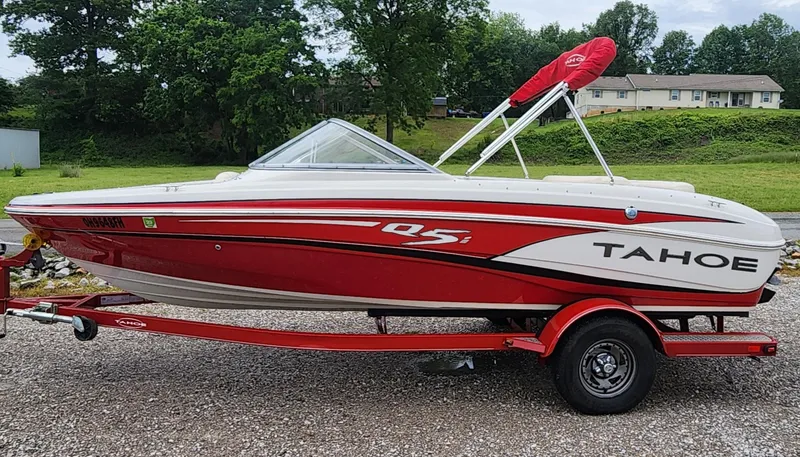 Slide: The Image of 2013 Tahoe Q5i boat, red and white, on trailer, parked outdoors. - 2
