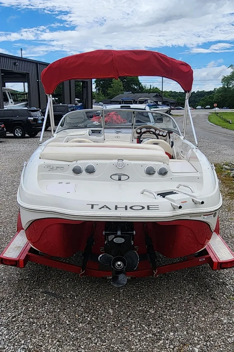 Slide: The Image of 2013 Tahoe Q5i boat with red canopy on a trailer, parked outdoors. - 3