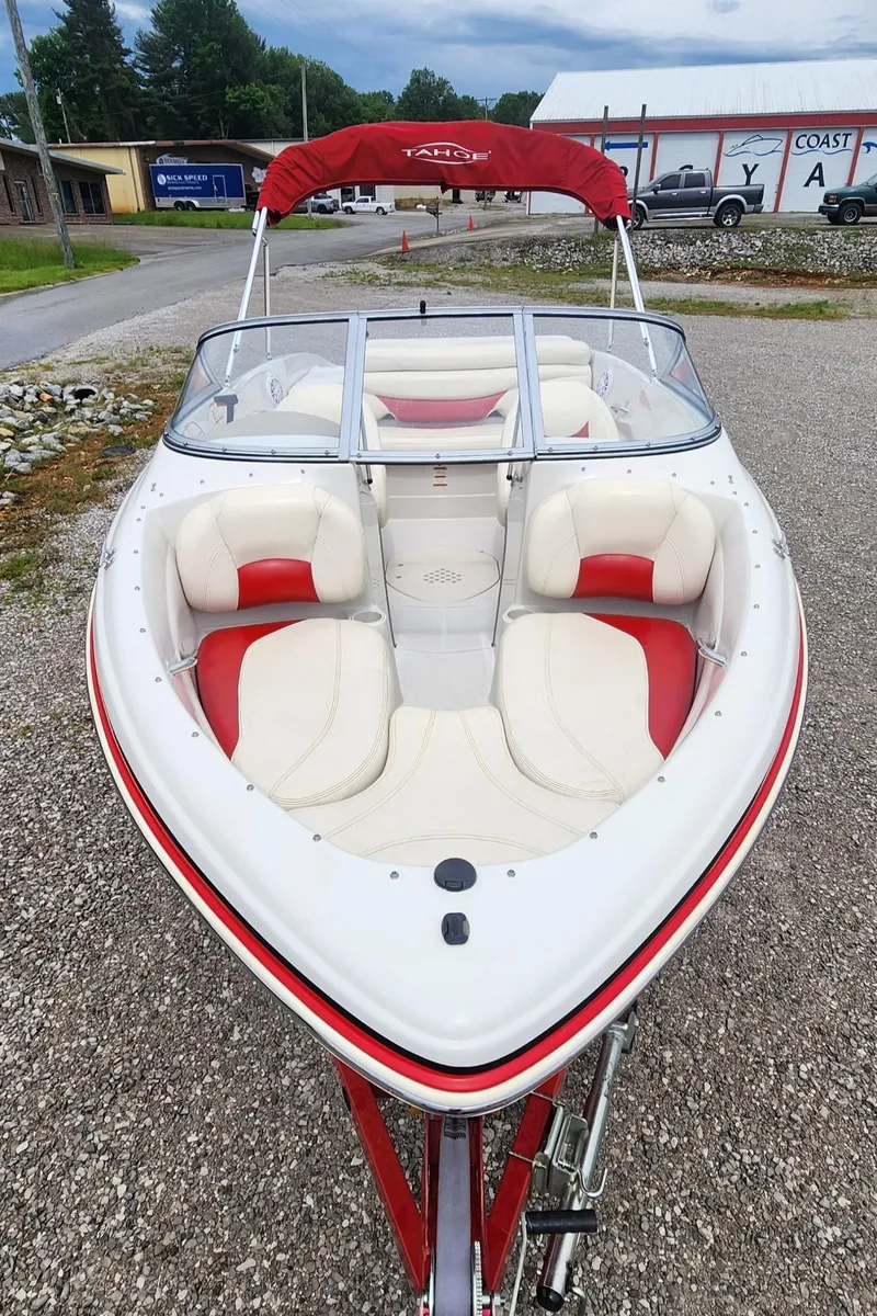 Slide: The Image of 2013 Tahoe Q5i boat with red and white seating, parked on gravel. - 4