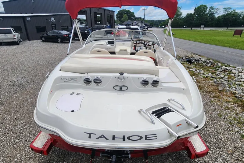 Slide: The Image of 2013 Tahoe Q5i boat with red canopy, parked on gravel near a building. - 5