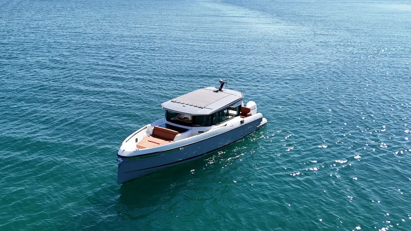 Slide: The Image of A 2026 Saxdor 320 GTC boat cruising on calm, blue water under a clear sky. - 3