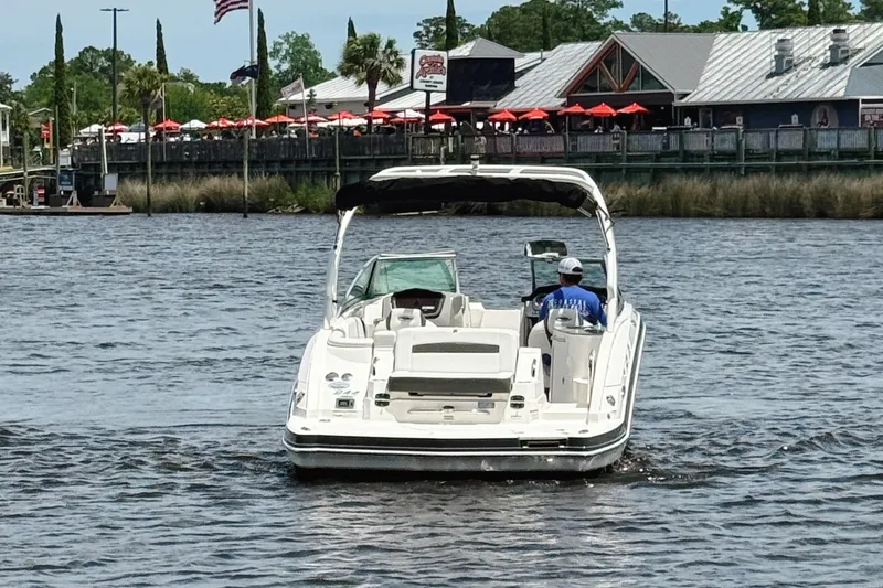 Slide: The Image of 2015 Chaparral 244 Sunesta boat cruising on a river near a waterfront restaurant. - 3